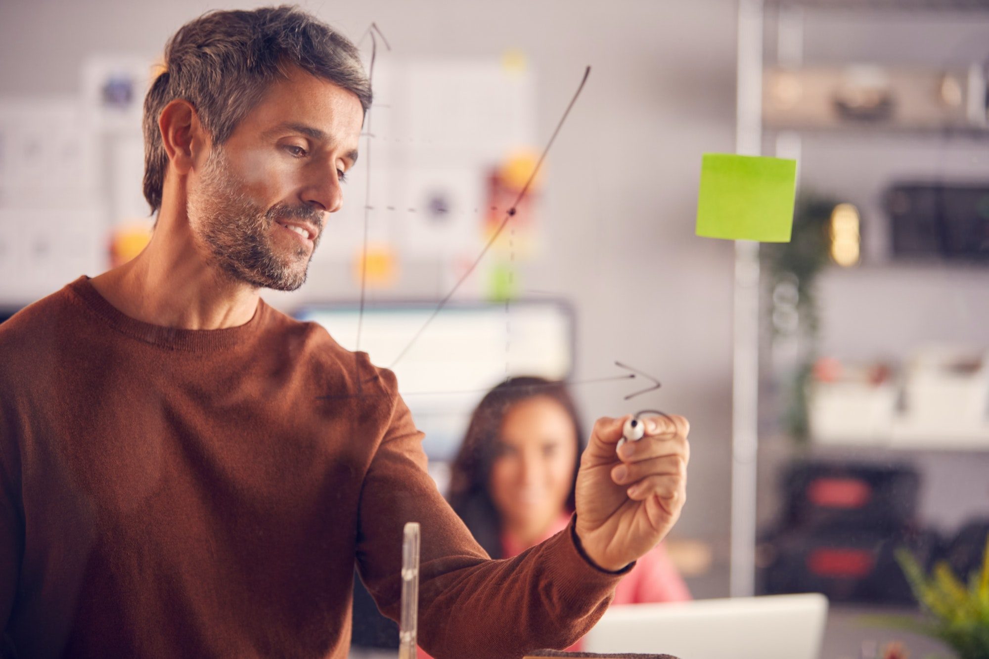 Brainstorming Creative Business Team Drawing Graph Onto Glass Screen In Office